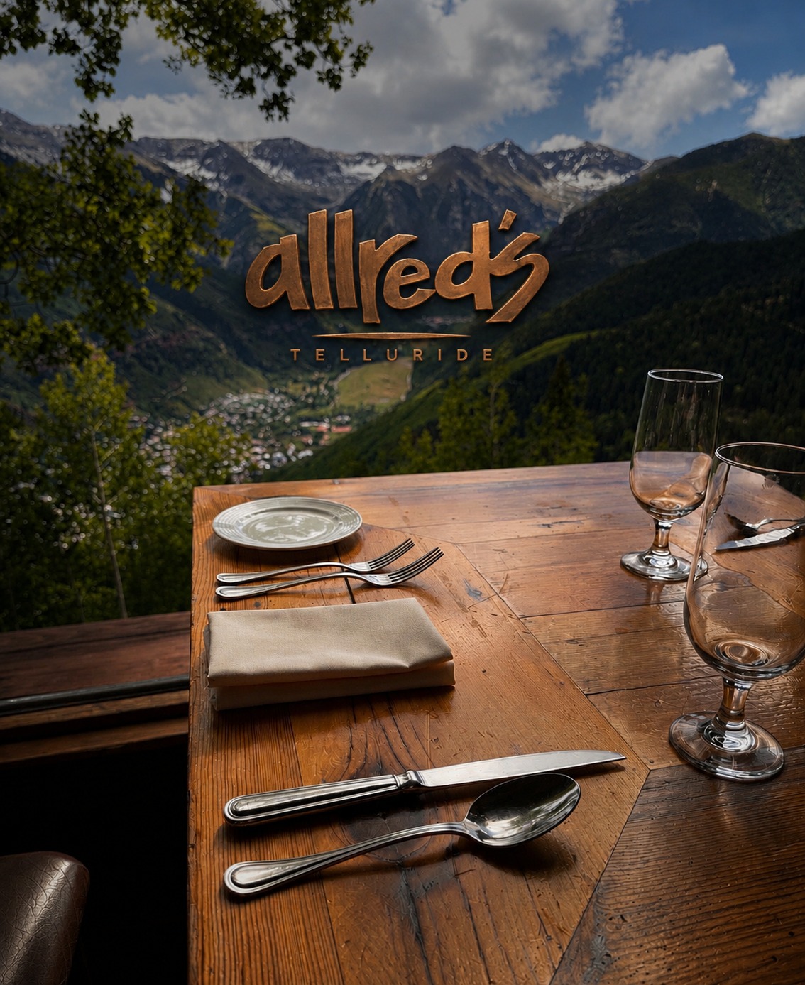 A table set outdoors at Allred's, overlooking the Telluride valley and San Juan Mountains, with the Allred's at Telluride logo