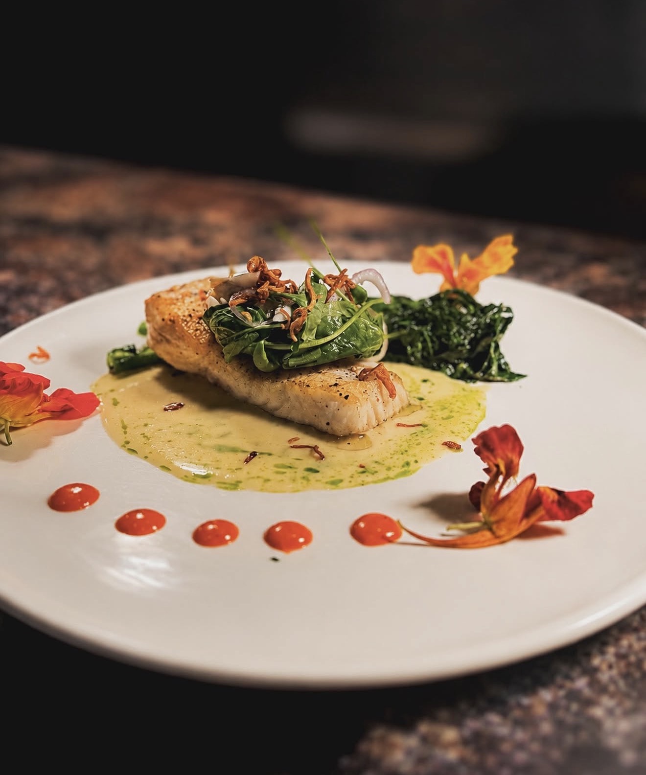 Seared halibut with wilted greens and nasturtium flowers, a plated course at Allred's